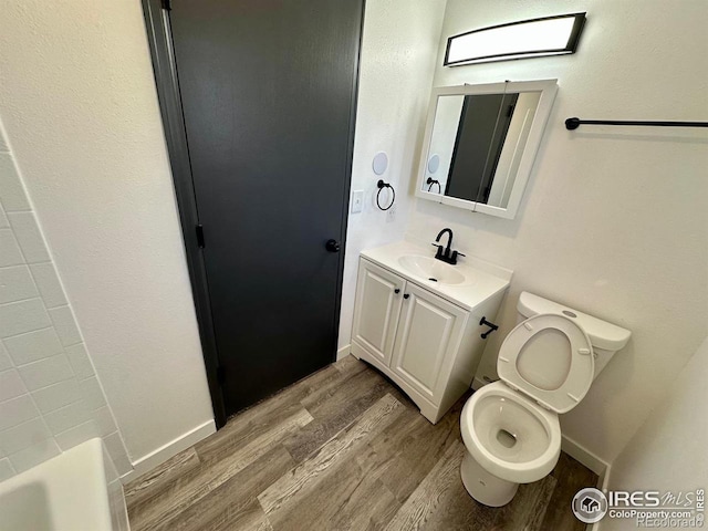 full bathroom featuring a bathtub, toilet, vanity, wood finished floors, and baseboards