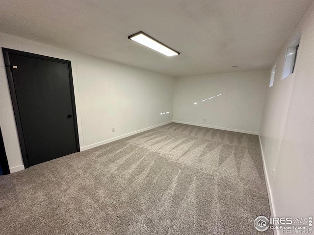 spare room featuring carpet floors, a textured ceiling, and baseboards