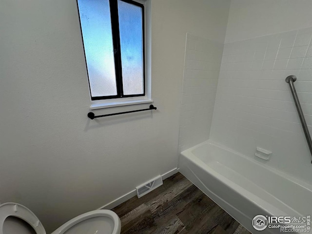 full bathroom featuring bathtub / shower combination, visible vents, toilet, wood finished floors, and baseboards