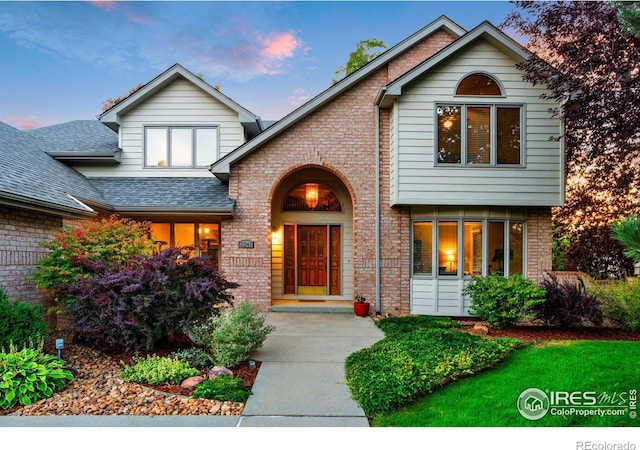 view of front of house featuring brick siding and roof with shingles