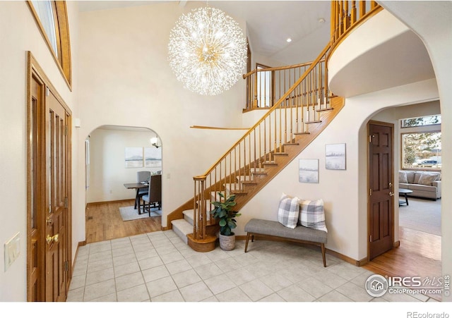 foyer with a chandelier, arched walkways, a high ceiling, and stairs