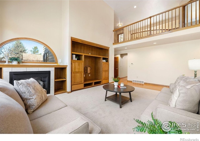 living area featuring a fireplace, a towering ceiling, visible vents, and recessed lighting