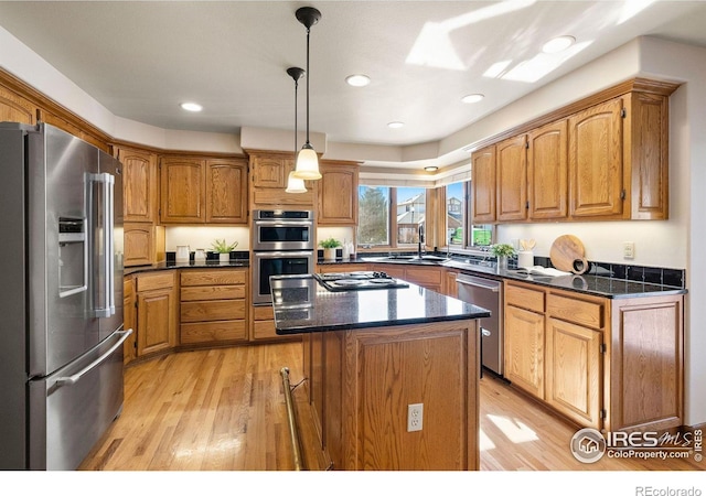 kitchen featuring light wood-style flooring, a kitchen island, appliances with stainless steel finishes, and brown cabinetry