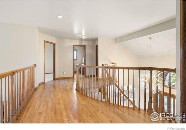 hall with baseboards, wood finished floors, vaulted ceiling with beams, an inviting chandelier, and an upstairs landing