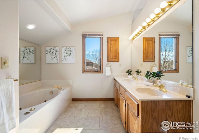 bathroom with lofted ceiling, a garden tub, baseboards, and a sink