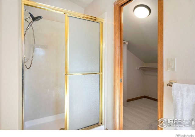 full bathroom featuring lofted ceiling, a shower with shower door, and baseboards