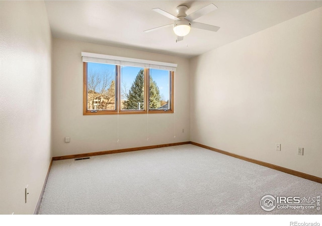 carpeted spare room with baseboards, visible vents, and ceiling fan