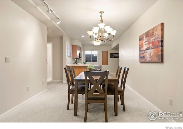 dining area featuring a chandelier, track lighting, baseboards, and light colored carpet