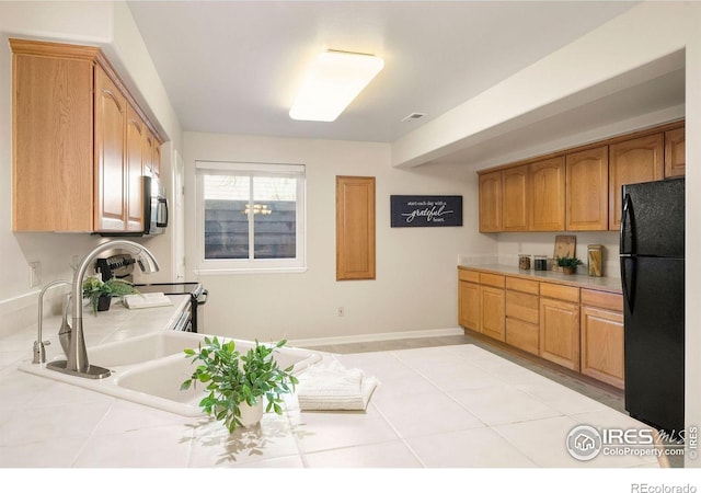 kitchen featuring tile countertops, black appliances, light tile patterned floors, and baseboards