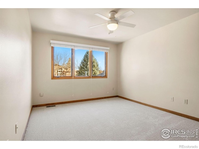 spare room with carpet flooring, a ceiling fan, baseboards, and visible vents