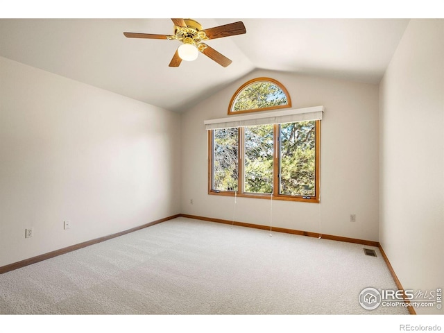 carpeted spare room featuring baseboards, ceiling fan, lofted ceiling, and visible vents