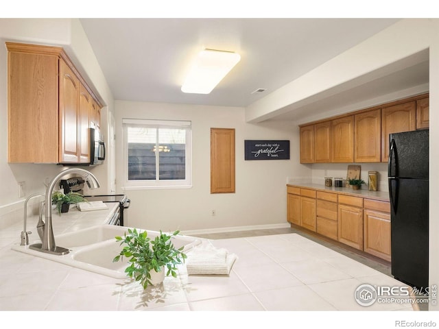 kitchen featuring visible vents, freestanding refrigerator, baseboards, tile counters, and light tile patterned floors