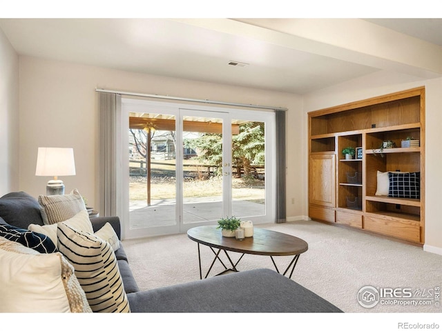 living area featuring visible vents, baseboards, and light carpet