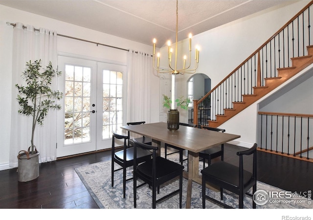 dining space with arched walkways, stairway, dark wood-style flooring, french doors, and a notable chandelier