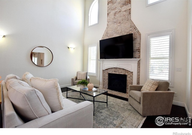 living room with plenty of natural light, a fireplace, a towering ceiling, and baseboards