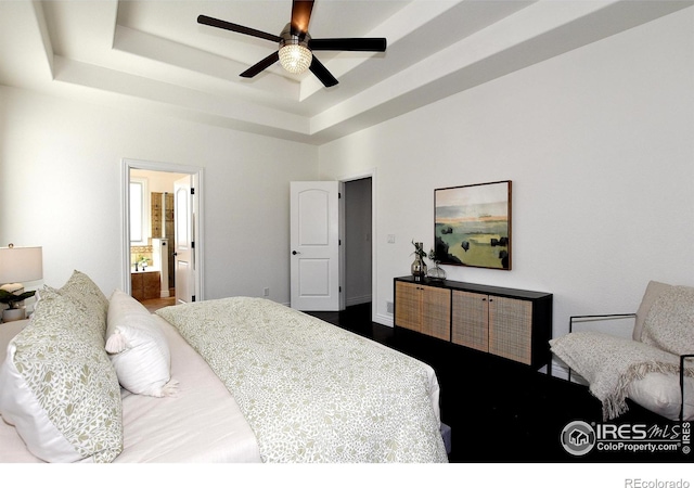 bedroom featuring a tray ceiling, a ceiling fan, and ensuite bathroom