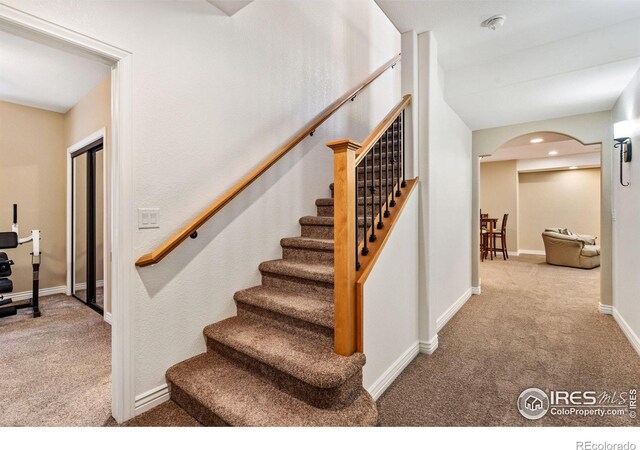 stairs featuring arched walkways, recessed lighting, carpet flooring, and baseboards