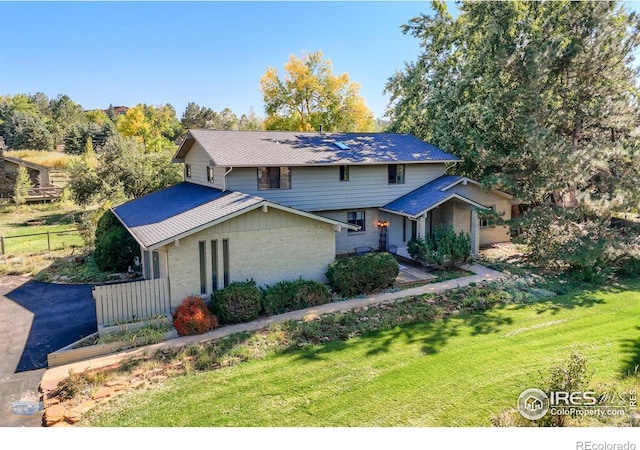 view of front of property featuring brick siding, a front yard, and fence