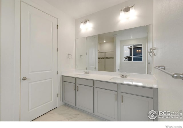 bathroom featuring marble finish floor, double vanity, a sink, and a shower stall