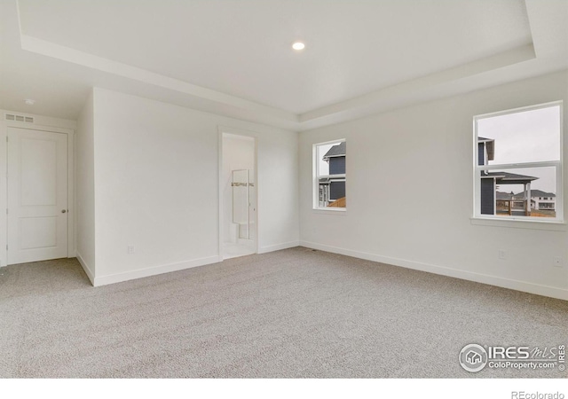 carpeted spare room with recessed lighting, a raised ceiling, visible vents, and baseboards