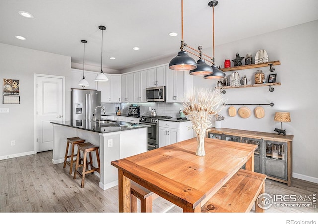 kitchen featuring dark countertops, white cabinetry, appliances with stainless steel finishes, and a sink