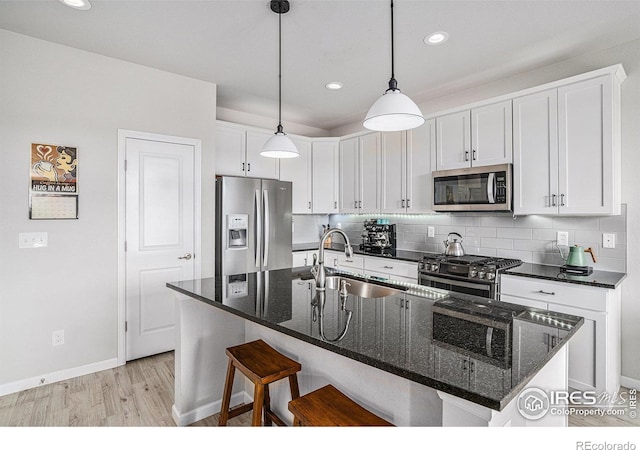 kitchen featuring a kitchen island with sink, appliances with stainless steel finishes, a sink, and white cabinetry