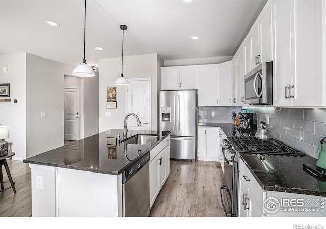 kitchen featuring stainless steel appliances, a center island with sink, a sink, and white cabinetry