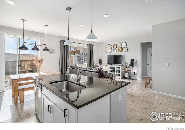 kitchen featuring dark countertops, white cabinets, a sink, and decorative light fixtures