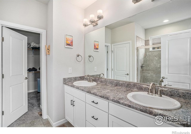 bathroom featuring a sink, a spacious closet, a shower stall, and double vanity