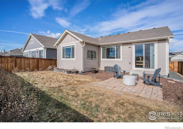 rear view of property with an outdoor fire pit, a lawn, a fenced backyard, a patio area, and board and batten siding