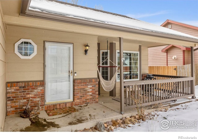 snow covered property entrance featuring brick siding