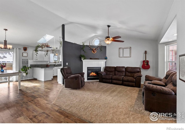 326 Riviera Ln, Johnstown, CO 80534 - living room featuring a tiled fireplace, ceiling fan, vaulted ceiling, and wood finished floors