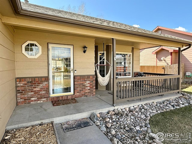 326 Riviera Ln, Johnstown, CO 80534 - doorway to property featuring covered porch, brick siding, and roof with shingles