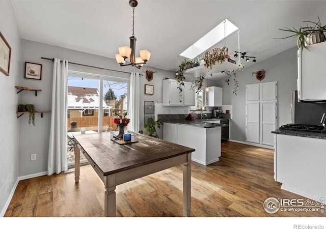 326 Riviera Ln, Johnstown, CO 80534 - kitchen featuring a chandelier, freestanding refrigerator, white cabinetry, a peninsula, and dark countertops