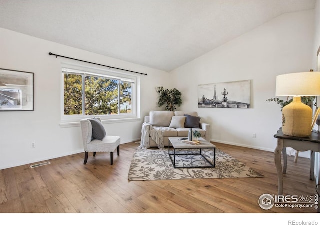 sitting room featuring lofted ceiling, visible vents, baseboards, and wood finished floors