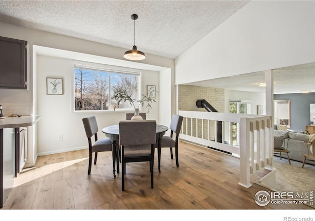 dining room with lofted ceiling, light wood-style flooring, and a healthy amount of sunlight