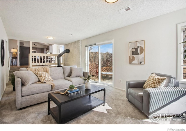 living room with light carpet, a wood stove, visible vents, and a textured ceiling