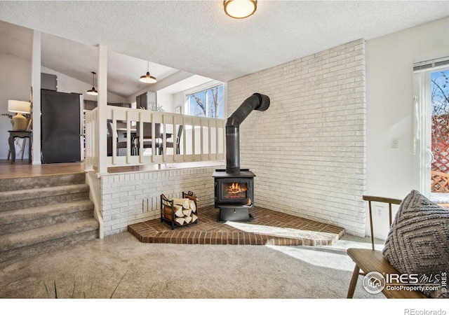 interior space with carpet floors, freestanding refrigerator, a wood stove, and a textured ceiling