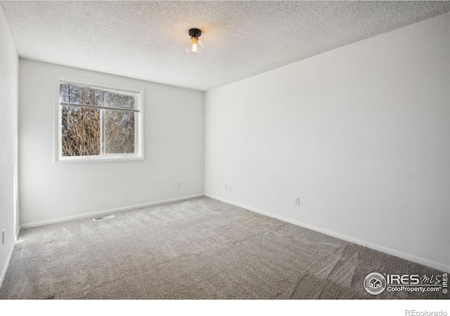 empty room featuring carpet floors, visible vents, baseboards, and a textured ceiling