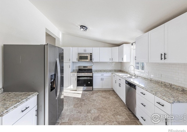 kitchen with lofted ceiling, stainless steel appliances, a sink, and white cabinets