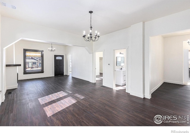 interior space featuring a notable chandelier, a sink, visible vents, baseboards, and dark wood-style floors