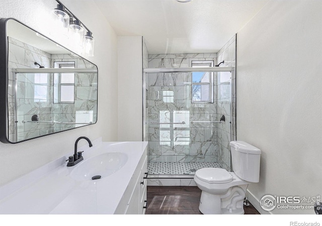 bathroom with vanity, a stall shower, wood finished floors, and toilet