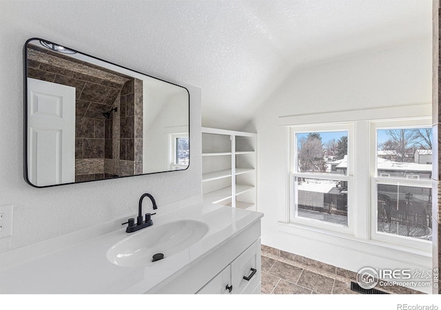 bathroom with a textured ceiling, lofted ceiling, and vanity