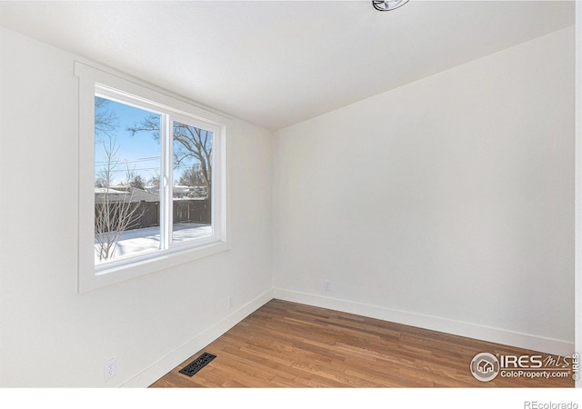 spare room featuring visible vents, baseboards, and wood finished floors