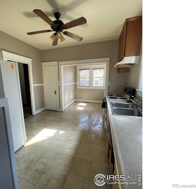 kitchen featuring white appliances, baseboards, ceiling fan, under cabinet range hood, and a sink