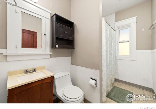 full bath with toilet, wainscoting, a shower with shower curtain, and vanity