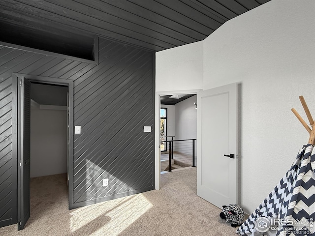 interior space with carpet, an upstairs landing, and wooden walls