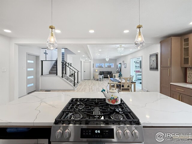 kitchen featuring open floor plan, stainless steel gas range oven, glass insert cabinets, and recessed lighting