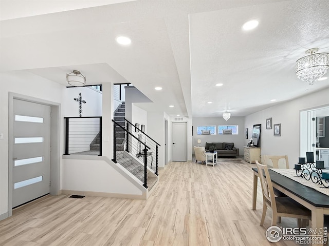 foyer entrance with a textured ceiling, recessed lighting, a notable chandelier, wood finished floors, and stairs