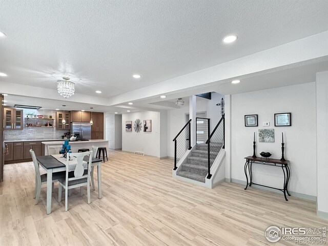 dining room featuring light wood finished floors, stairway, a textured ceiling, and recessed lighting